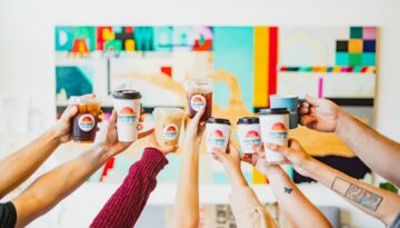 A group of people holding up cups of coffee from Driftwood Coffee Co.