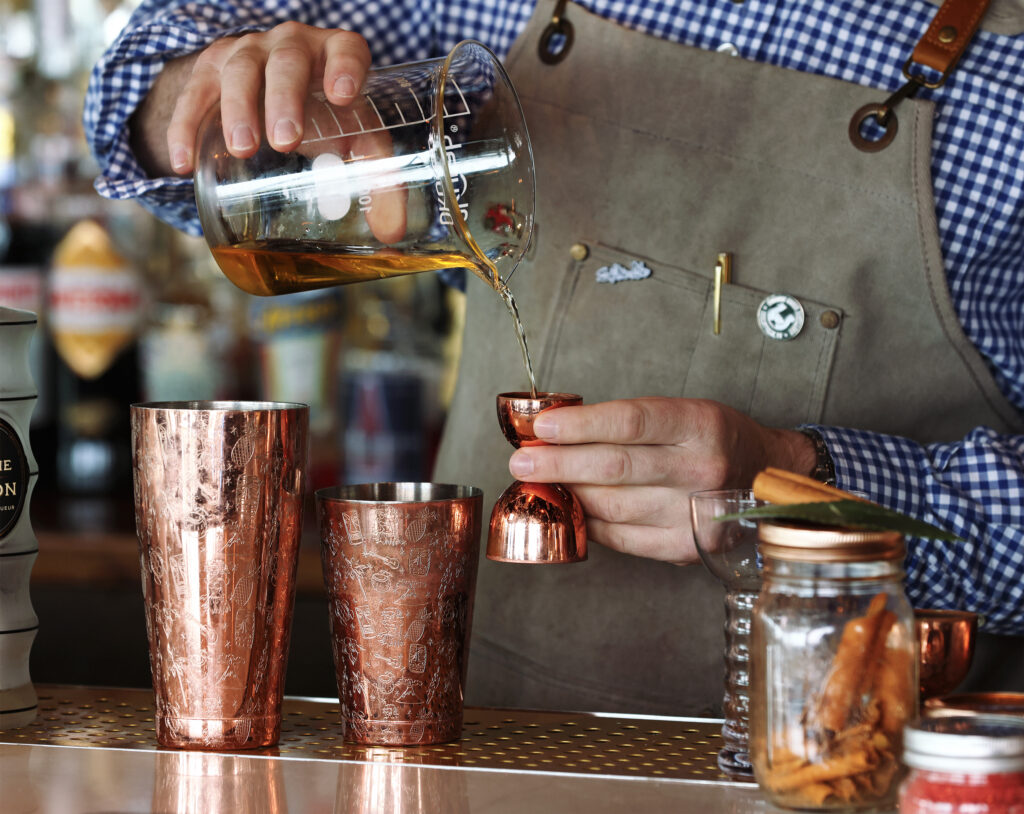 Mixologist measuring ingredients for a drink.