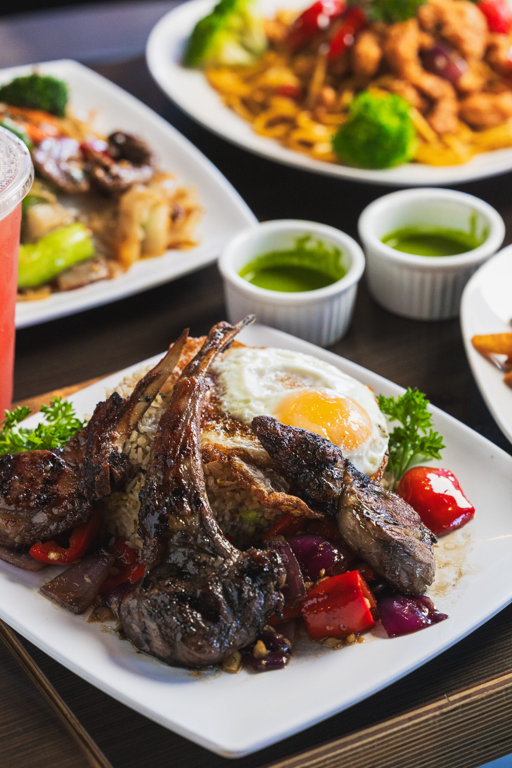 Lamb chops and an over-easy egg laid on a white dish, from Kapi Honda.